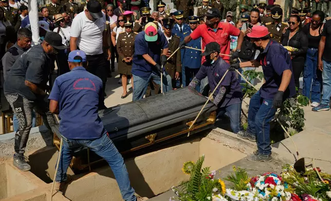 Cemetery workers lower the casket of a soldier killed in the U.S. raid to capture Venezuelan President Nicolas Maduro and his wife into the ground in Caracas, Venezuela, Wednesday, Jan. 7, 2026. (AP Photo/Ariana Cubillos)