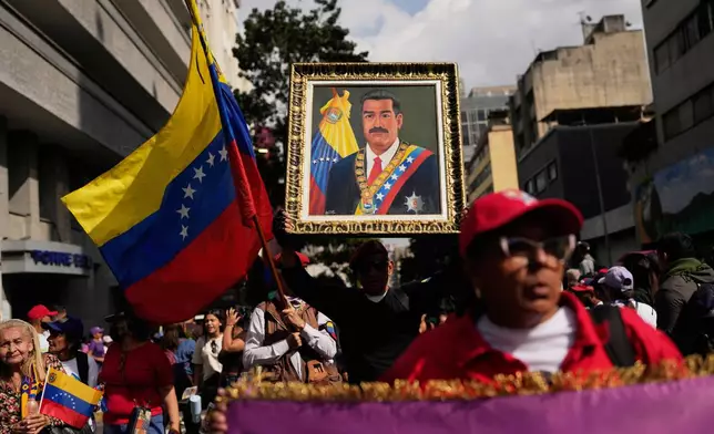 FILE - A government supporter holds an image of President Nicolas Maduro during a women's march to demand his return in Caracas, Venezuela, Jan. 6, 2026, three days after U.S. forces captured him and his wife. (AP Photo/Matias Delacroix, File)