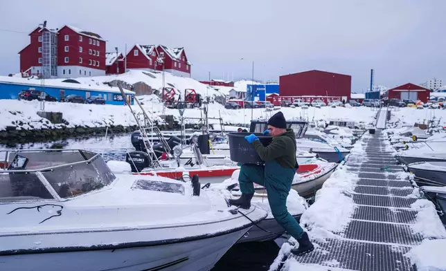 A fisherman carries a bucket onto his boat in the harbor of Nuuk, Greenland, on Tuesday, Jan. 13, 2026. (AP Photo/Evgeniy Maloletka)