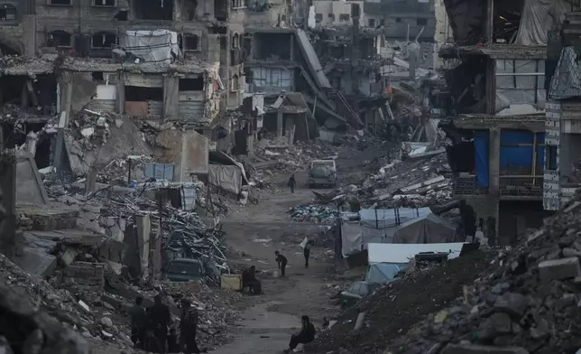 Palestinians walk amid buildings destroyed by Israeli air and ground operations in Gaza City Tuesday, Jan. 6, 2026. (AP Photo/Jehad Alshrafi)
