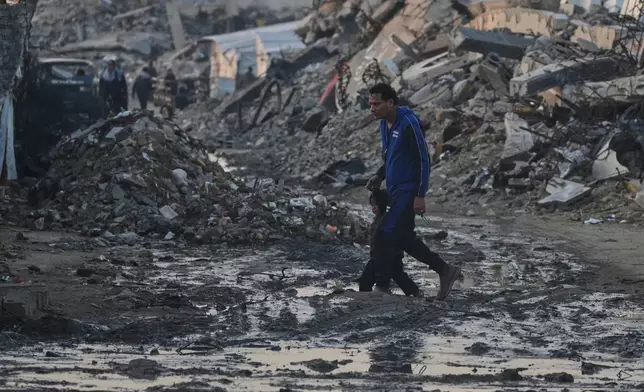 Palestinians walk amid buildings destroyed by Israeli air and ground operations in Gaza City Tuesday, Jan. 6, 2026. (AP Photo/Jehad Alshrafi)