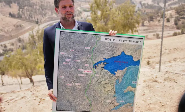 FILE - Israeli Finance Minister Bezalel Smotrich holds a map that shows the E1 settlement project during a press conference near the settlement of Maale Adumim, in the Israeli-occupied West Bank, Aug. 14, 2025. (AP Photo/Ohad Zwigenberg, File)