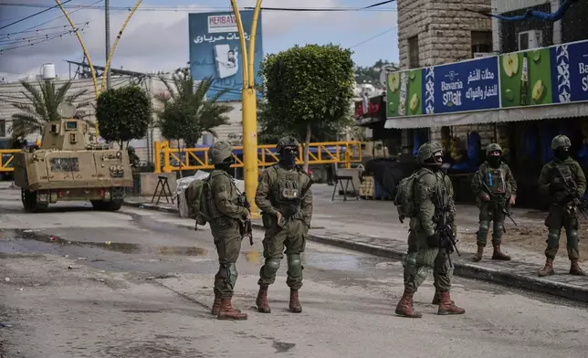 Israeli soldiers take up positions during an army raid in the West Bank city of Hebron Monday, Jan. 19, 2026. (AP Photo/Mahmoud Illean)