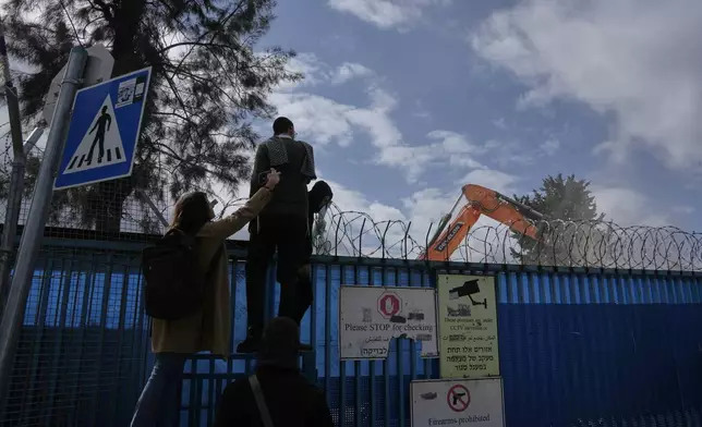 People watch the demolition of a UNRWA compound, the U.N. agency that assists Palestinian refugees, in east Jerusalem Tuesday, Jan. 20, 2026. (AP Photo/Mahmoud Illean)