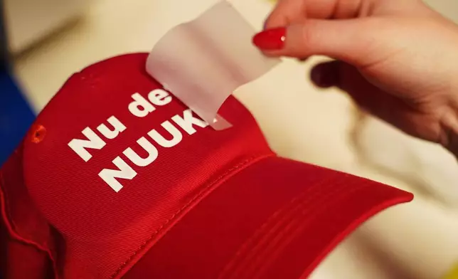 A worker prints a red cap for with the slogan "Nu det NUUK!," a twist on the Danish phrase “Nu det nok,” meaning “Now it’s enough,” substituting Nuuk, Greenland’s tiny capital, for sale at the store of the hat's creator Jesper Rabe Tonnesen in Copenhagen, Denmark, Friday, Jan. 16, 2026. (AP Photo/James Brooks)