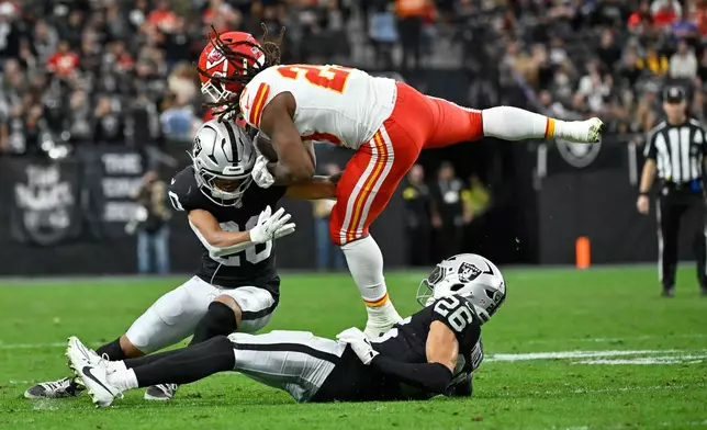 Kansas City Chiefs running back Kareem Hunt (29) runs with the ball as Las Vegas Raiders safety Isaiah Pola-Mao, left, and cornerback Darien Porter (26) defend during the first half of an NFL football game Sunday, Jan. 4, 2026, in Las Vegas. (AP Photo/David Becker)