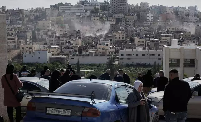 People watch an Israeli army bulldozer demolishing homes in the Palestinian urban refugee camp of Nur Shams, near the West Bank city of Tulkarem, Wednesday, Dec. 31, 2025. (AP Photo/Majdi Mohammed)