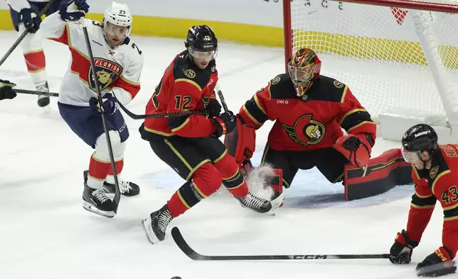 Florida Panthers' Carter Verhaeghe (23), Ottawa Senators' Shane Pinto (12) and Senators' Tyler Kleven (43) scramble for the puck in front of Senators goaltender Leevi Merilainen (1) during first-period NHL hockey game action in Ottawa, Ontario, Saturday, Jan. 10, 2026. (Patrick Doyle/The Canadian Press via AP)