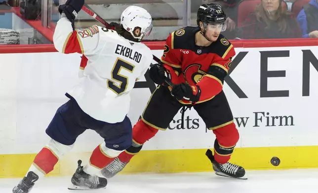 Florida Panthers' Aaron Ekblad (5) and Ottawa Senators' Shane Pinto (12) battle for the puck during second period NHL hockey action in Ottawa on Saturday, Jan. 10, 2026. (Patrick Doyle/The Canadian Press via AP)