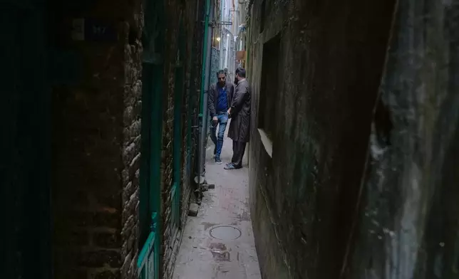 A local make way for another for walking through a narrow alley in an old neighborhood of Lahore, Pakistan, Friday, Dec. 12, 2025. (AP Photo/K.M. Chuadary)