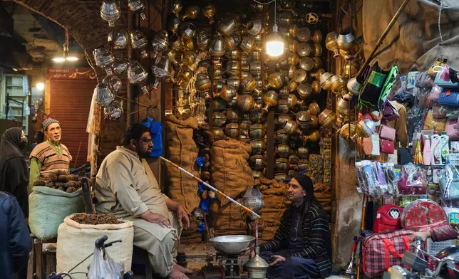 A vendor chats with his friend at his hookah, or water-pipe shop, in an old neighborhood of Lahore, Pakistan, Saturday, Dec. 6, 2025. (AP Photo/K.M. Chaudary)