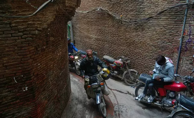 Motorcyclists drive through an alley in an old neighborhood in Lahore, Pakistan, Tuesday, Dec. 30, 2025. (AP Photo/K.M. Chaudary)