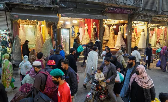 Local resident walks through a market of traditional embroidery bridal dresses in an old neighborhood of Lahore, Pakistan, Monday, Dec. 8, 2025. (AP Photo/K.M. Chaudary)