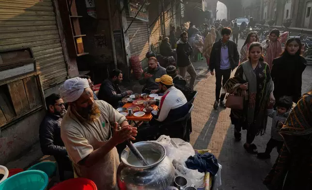 A vendor prepares traditional yogurt mixed drink locally called Lassi for customers at a street of an old neighborhood of Lahore, Pakistan, Sunday, Dec. 7, 2025. (AP Photo/K.M. Chaudary)