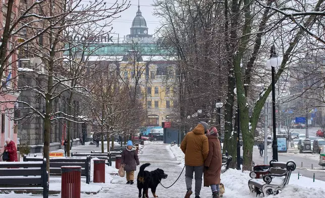 A couple share a tender moment as they walk on a snowy street in Kyiv, Ukraine, Thursday, Jan. 8, 2026, as Ukraine faces harsh weather amid Russia's regular missile attacks on the country's energy system. (AP Photo/Efrem Lukatsky)