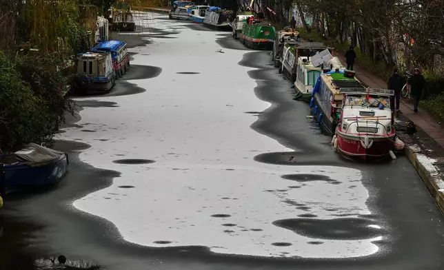 Narrowboats are anchored on a frozen canal after light snowfall in London, Tuesday, Jan. 6, 2026 as new warnings have been issued for more wintry weather. (AP Photo/Frank Augstein)
