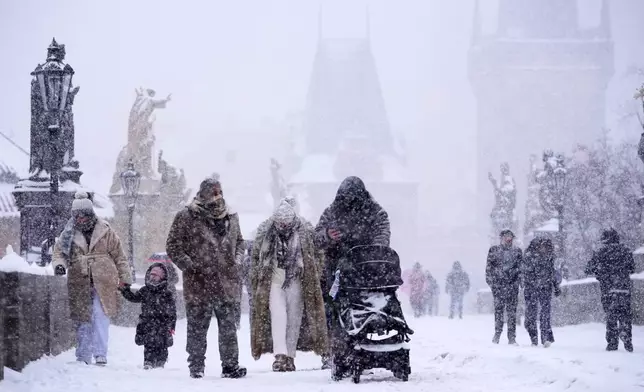 People cross the medieval Charles Bridge during a heavy snowfall in Prague, Czech Republic, Friday, Jan. 9, 2026. (AP Photo/Petr David Josek)