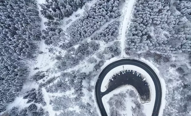 Cars drive around a curve in a snow covered forest of the Taunus region near Frankfurt, Germany, Tuesday, Jan. 6, 2026. (AP Photo/Michael Probst)