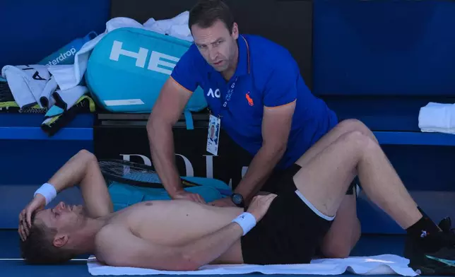 Yannick Hanfmann of Germany receives treatment from a trainer during his second round match against Carlos Alcaraz of Spain at the Australian Open tennis championship in Melbourne, Australia, Wednesday, Jan. 21, 2026. (AP Photo/Dita Alangkara)