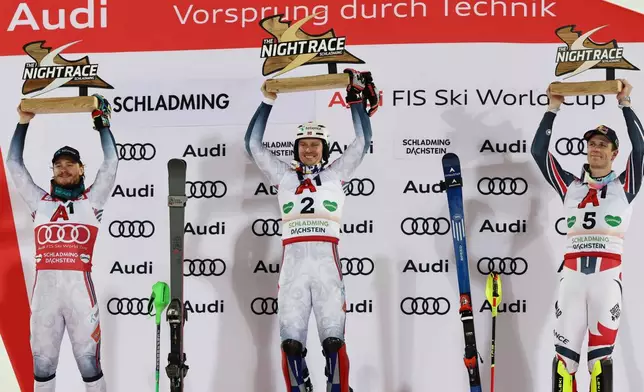 Norway's Henrik Kristoffersen, center, winner of an alpine ski, men's World Cup slalom, celebrates on the podium with second-placed Norway's Atle Lie McGrath, left, and third-placed France's Clement Noel, in Schladming, Austria, Wednesday, Jan. 28, 2026. (AP Photo/Marco Trovati)