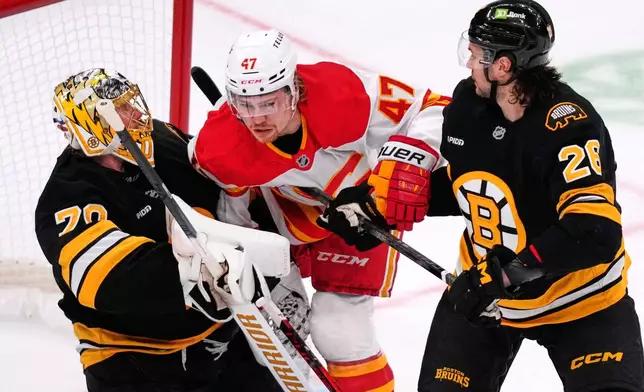 Calgary Flames center Connor Zary (47) collides with Boston Bruins goaltender Joonas Korpisalo (70), as Bruins defenseman Andrew Peeke (26) looks on, during the first period of an NHL hockey game, Thursday, Jan. 8, 2026, in Boston. (AP Photo/Charles Krupa)