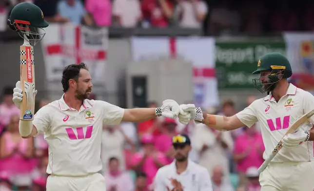 Australia's Travis Head is congratulated by teammate Michael Neser, right, after scoring a century during play on day three of the fifth and final Ashes cricket test between England and Australia in Sydney, Tuesday, Jan. 6, 2026. (AP Photo/Mark Baker)