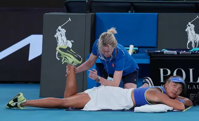 Yuan Yue of China receives treatment from a trainer during her first round match against Iga Swiatek of Poland at the Australian Open tennis championship in Melbourne, Australia, Monday, Jan. 19, 2026. (AP Photo/Aaron Favila)