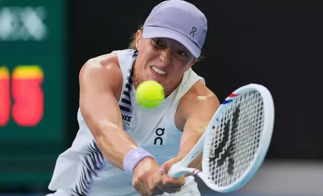 Iga Swiatek of Poland plays a backhand return to Yuan Yue of China during their first round match at the Australian Open tennis championship in Melbourne, Australia, Monday, Jan. 19, 2026. (AP Photo/Aaron Favila)