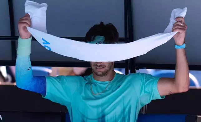 Lorenzo Musetti of Italy puts an ice towel around his face during a break in his third round match against Tomas Machac of the Czech Republic at the Australian Open tennis championship in Melbourne, Australia, Saturday, Jan. 24, 2026. (AP Photo/Asanka Brendon Ratnayake)