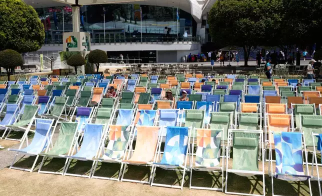 Fans sit in the shade as they watch quarterfinal matches on a video screen at the Australian Open tennis championship in Melbourne, Australia, Tuesday, Jan. 27, 2026. (AP Photo/Dar Yasin)