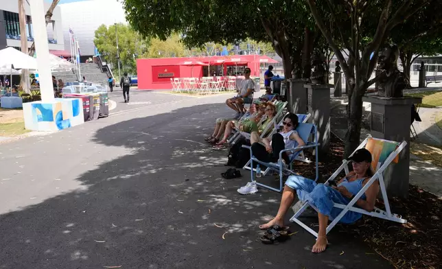 Fans sit in the shade as they watch quarterfinal matches on a video screen at the Australian Open tennis championship in Melbourne, Australia, Tuesday, Jan. 27, 2026. (AP Photo/Dar Yasin)