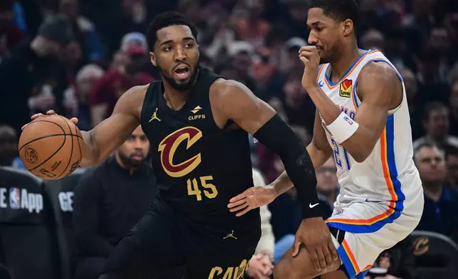Cleveland Cavaliers guard Donovan Mitchell (45) drives against Oklahoma City Thunder guard Aaron Wiggins, right, in the first half of an NBA basketball game, Monday, Jan. 19, 2026, in Cleveland. (AP Photo/David Dermer)
