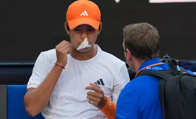 Learner Tien of the U.S. receives treatment for a nose bleed during his fourth round match against Daniil Medvedev of Russia at the Australian Open tennis championship in Melbourne, Australia, Sunday, Jan. 25, 2026. (AP Photo/Asanka Brendon Ratnayake)