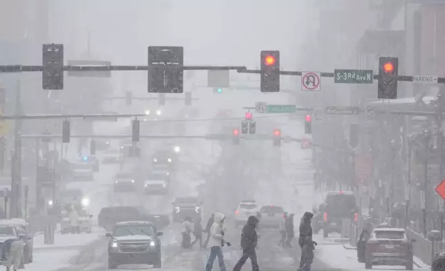 Pedestrians cross the street along Broadway during a winter storm Saturday, Jan. 24, 2026, in Nashville, Tenn. (AP Photo/George Walker IV)