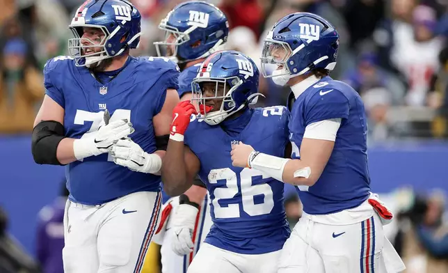 New York Giants running back Devin Singletary (26) celebrates with quarterback Jaxson Dart (6) and guard Greg van Roten (74) after scoring a touchdown against the Dallas Cowboys during the fourth quarter of an NFL football game, Sunday, Jan. 4, 2026, in East Rutherford, N.J. (AP Photo/Adam Hunger)