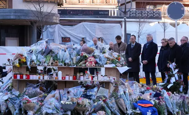 Swiss Minister of Justice Beat Jans and State Councillor Mathias Reynard lay flowers at the sealed off Le Constellation bar in Crans-Montana, Swiss Alps, Switzerland, Saturday, Jan. 3, 2026, where a devastating fire left dead and injured during the New Year's celebrations. (AP Photo/Antonio Calanni)
