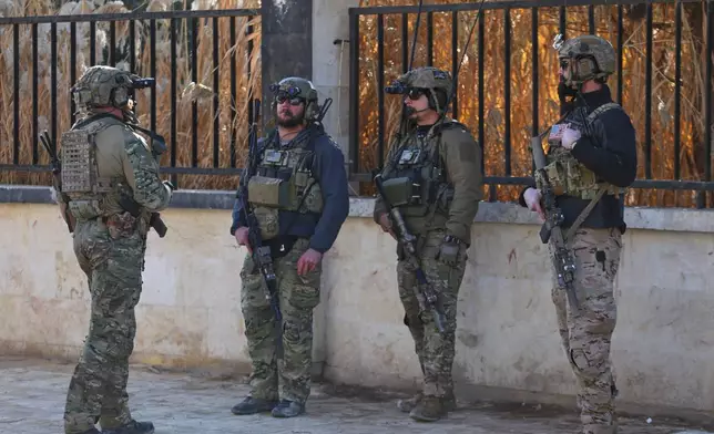 American soldiers from the U.S.-led coalition against the Islamic State group stand guard during a meeting with the U.S.-backed Syrian Democratic Forces in Deir Hafer, Syria, Friday, Jan. 16, 2026. (AP Photo/Baderkhan Ahmad)