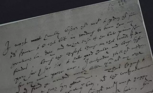 A 16th century letter written by Robert Dudley, 1st Earl of Leicester, to Queen Elizabeth I, on view during a preview of the Love Letters exhibition at the National Archives in London on Wednesday, Jan. 21, 2026, shows two dots written above the word poor, a reference to the monarch's nickname for Dudley: Eyes. (AP Photo/Alastair Grant)