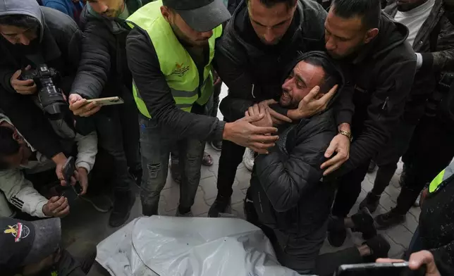 People mourn over the bodies of the Palestinian journalists Abd Shaat and Mohamed Qeshta, who were killed in an Israeli strike on a vehicle, before their funeral at Shifa Hospital, in Gaza City, Wednesday, Jan. 21, 2026. (AP Photo/Jehad Alshrafi)