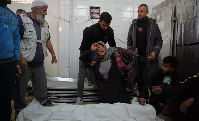Najwa Al-Rajoudi mourns over the body of her nephew Moussa Al-Rajoudi before his funeral at Al-Aqsa Hospital in Deir al-Balah, central Gaza Strip, Wednesday, Jan. 21, 2026, after he was killed in an Israeli fire. (AP Photo/Abdel Kareem Hana)