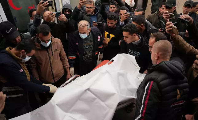 People carry the body of the Palestinian photographer Anas Ghoneim, who was killed in an Israeli strike on a vehicle, during his funeral at Al-Aqsa Hospital in Deir al-Balah, central Gaza Strip, Wednesday, Jan. 21, 2026.