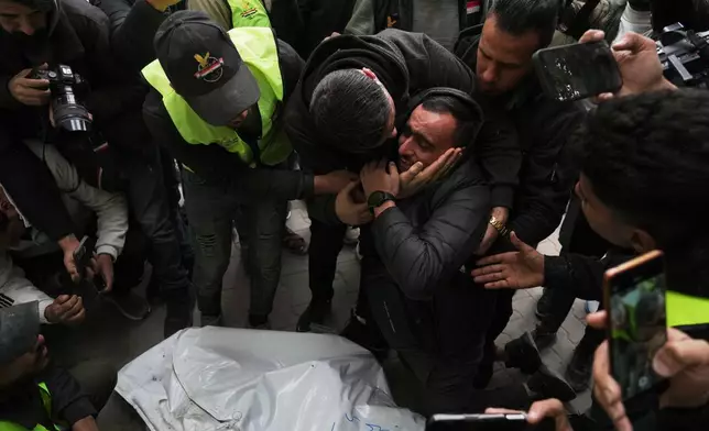 People mourn over the bodies of the Palestinian journalists Abd Shaat and Mohamed Qeshta, who were killed in an Israeli strike on a vehicle, before their funeral at Shifa Hospital, in Gaza City, Wednesday, Jan. 21, 2026. (AP Photo/Jehad Alshrafi)