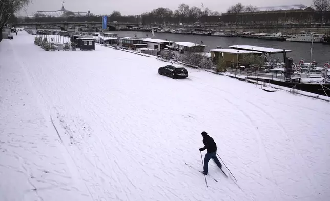 A person skies along the Seine river banks after a snowfall, Wednesday, Jan. 7, 2026 in Paris. (AP Photo/Christophe Ena)