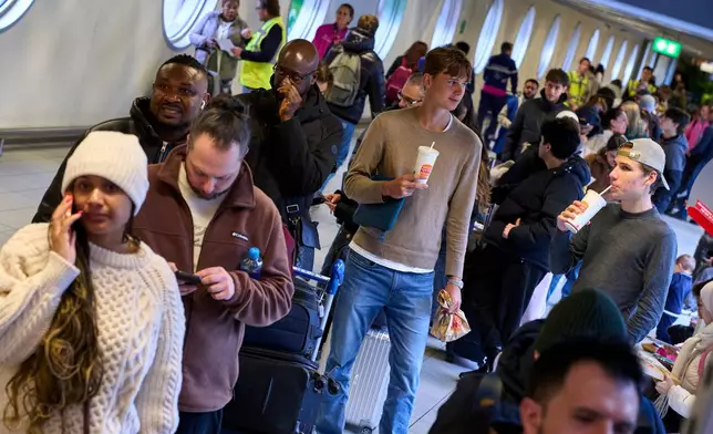 Stranded travellers queue at the information desk at Schiphol airport in Amsterdam, Netherlands, Wednesday, Jan. 7, 2026, where more than 1,000 people spent the night as snow and ice that is pummeling parts of Europe grounded hundreds of flights and choked highways and railroads. (AP Photo/Peter Dejong)