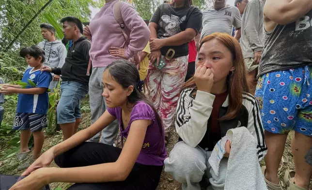 Relatives and others wait for updates after a huge mound of garbage collapsed at a waste segregation facility in Binaliw, Cebu city on Friday, Jan. 9, 2026. (AP Photo/Jacqueline Hernandez)