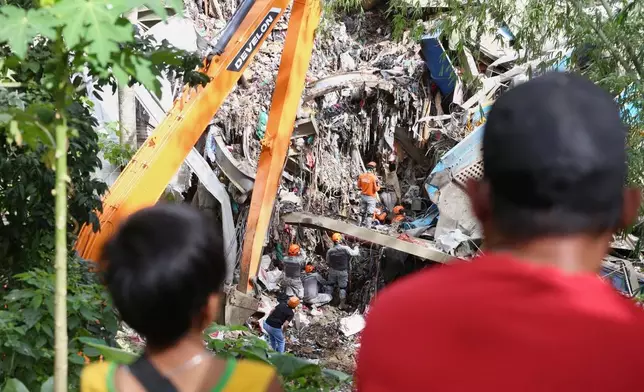 Relatives and family members watch as rescuers continue operations on a collapsed waste segregation facility in Binaliw, Cebu city, central Philippines on Saturday, Jan. 10, 2026. (AP Photo/Jacqueline Hernandez)