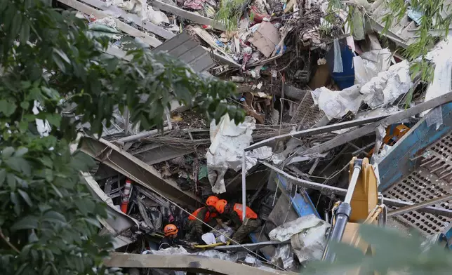 Rescuers retrieve a body inside a collapsed waste segregation facility in Binaliw, Cebu city, central Philippines on Friday, Jan. 9, 2026. (AP Photo/Jacqueline Hernandez)