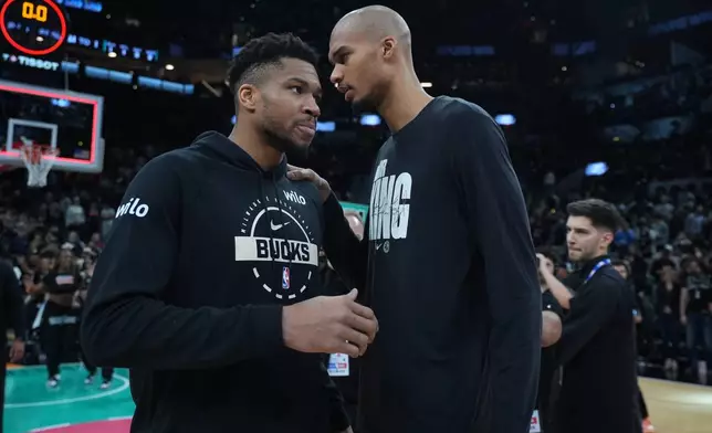 Milwaukee Bucks forward Giannis Antetokounmpo, left, and San Antonio Spurs forward Victor Wembanyama, right, visit following their NBA basketball game in San Antonio, Thursday, Jan. 15, 2026. (AP Photo/Eric Gay)