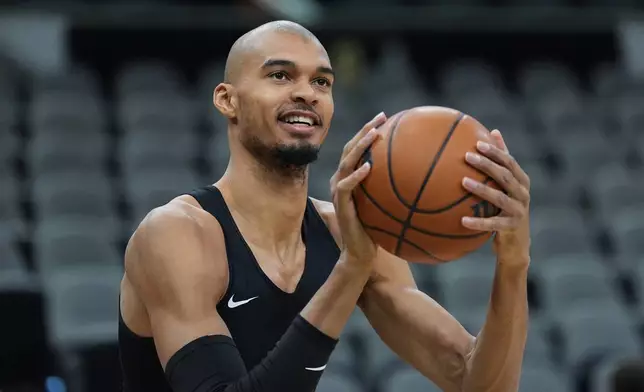 San Antonio Spurs forward Victor Wembanyama reveals a freshly shaved head as he warms up before an NBA basketball game against the Milwaukee Bucks in San Antonio, Thursday, Jan. 15, 2026. (AP Photo/Eric Gay)