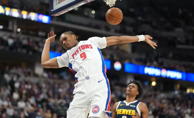 Detroit Pistons guard Ausar Thompson dunks the ball for a basket over Denver Nuggets guard Peyton Watson in the first half of an NBA basketball game Tuesday, Jan. 27, 2026, in Denver. (AP Photo/David Zalubowski)